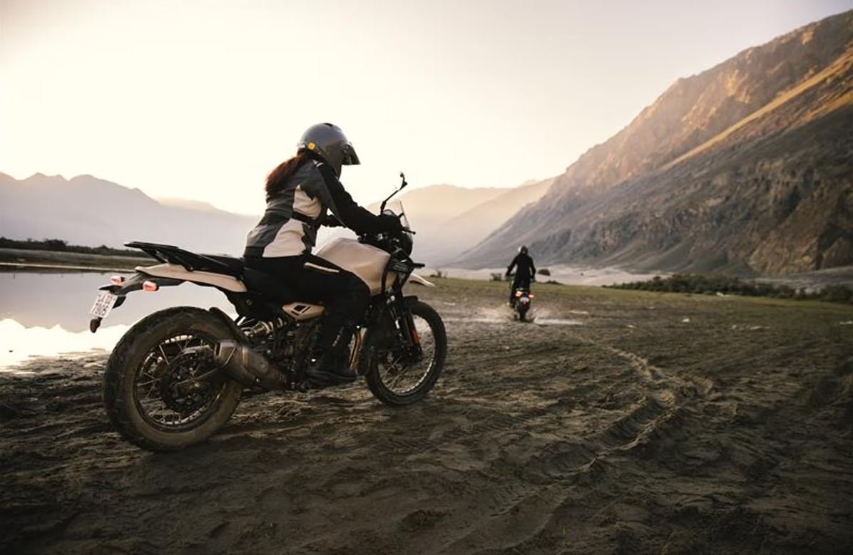 Motociclista y pasajero con casco certificado y equipo de protección rodando en carretera