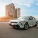 Kia K4 sedán compacto circulando en ciudad al atardecer, modelo ganador del premio Drivers Choice 2026 de MotorWeek