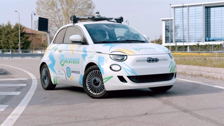 Vehículo eléctrico de car sharing autónomo llegando a un punto de recogida urbano