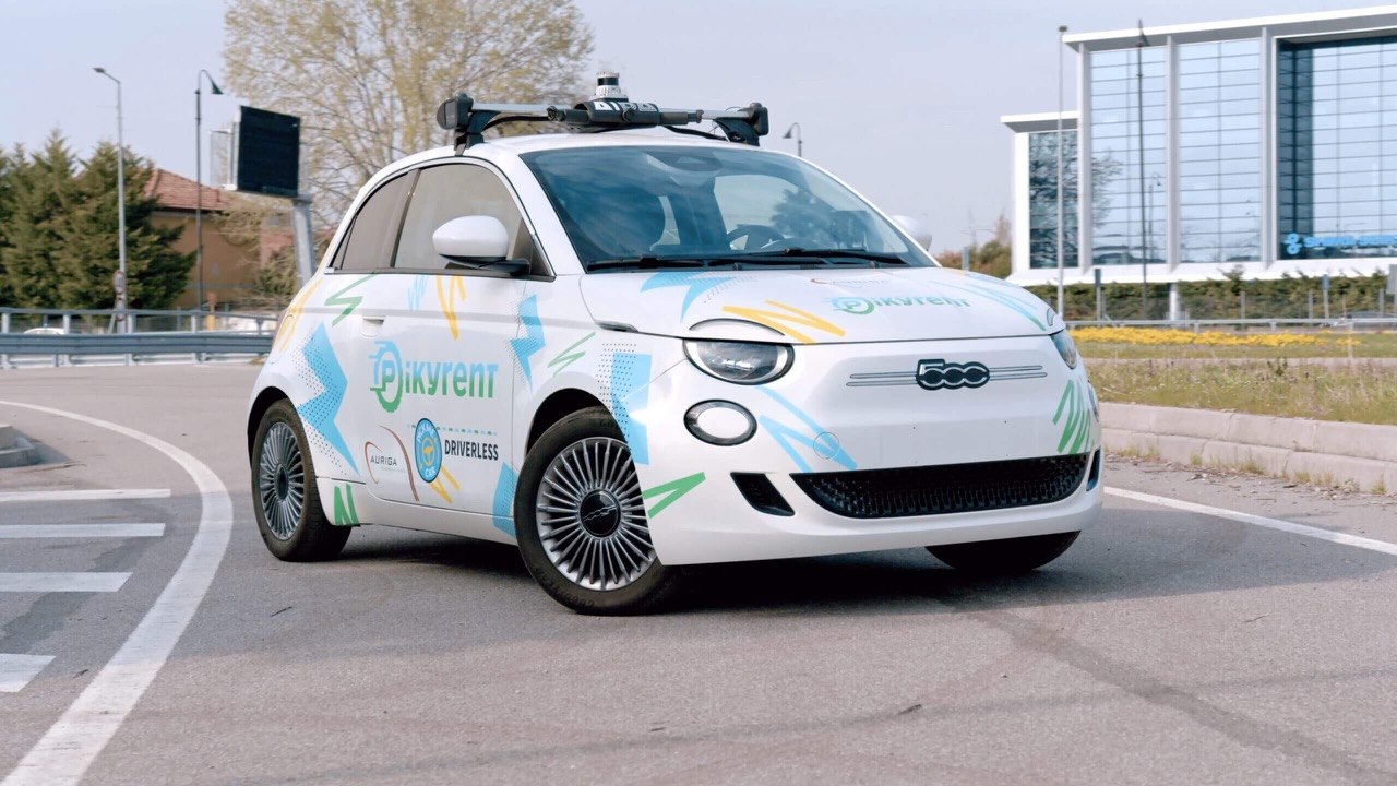 Vehículo eléctrico de car sharing autónomo llegando a un punto de recogida urbano
