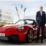 Directivo de Porsche junto a un 911 rojo frente a las instalaciones de la marca