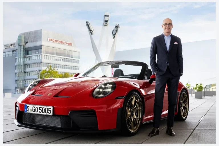 Directivo de Porsche junto a un 911 rojo frente a las instalaciones de la marca
